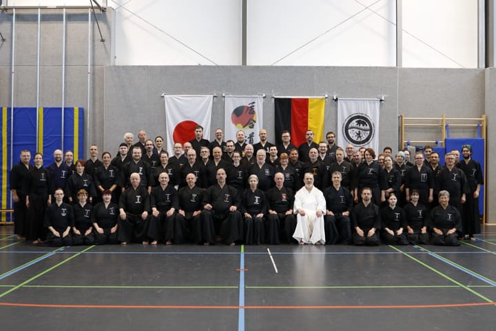 Die Teilnehmer und Teilnehmerinnen in traditionellem Hakama und Gi in drei Reihen (die erste sitzend)